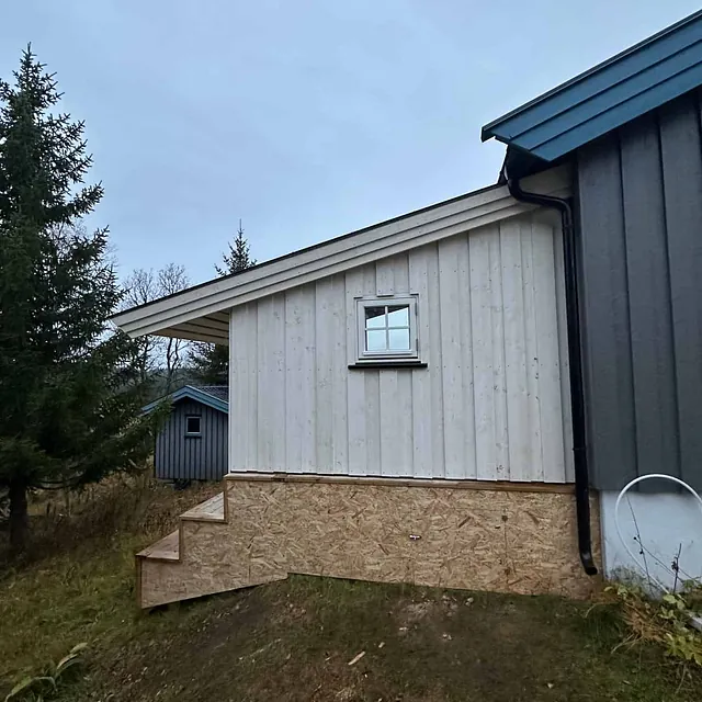 Ny kledning og trapp på husets sidevegg, kombinert med OSB-plater nederst.