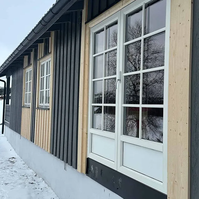 Fasade med nye vinduer og kombinasjon av lys og mørk kledning på trehus.